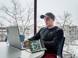 Nursing student sitting in front of a laptop with a book.